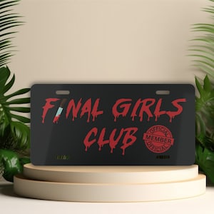 May include: Black metal license plate with red dripping text that reads "Final Girls Club" and a red stamp that reads "Official Member Official".