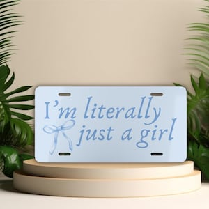 May include: A light blue license plate with the text "I'm literally just a girl" in a light blue cursive font. A light blue bow is above the text.