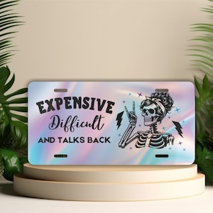 May include: A holographic license plate with a skeleton with a peace sign and the text "EXPENSIVE Difficult AND TALKS BACK".