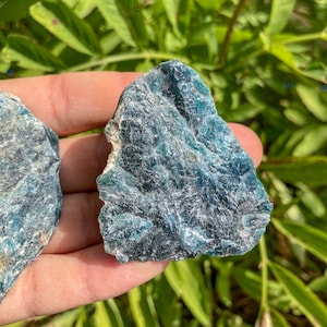 Puede incluir: Dos piezas de apatita bruta azul verdosa, un cristal popular para la curación y la meditación.