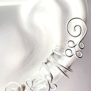 Funkelnde Ohrspange mit transparenter Glasperle und zarten Spiralen