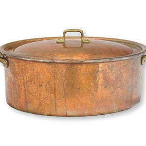 May include: A copper cooking pot with a lid. The pot has two side handles and a handle on the lid. The pot is a warm copper color with a slightly aged appearance. The handles are a lighter, brassy color.