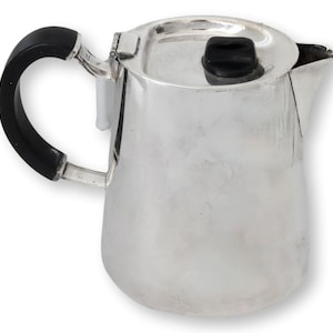 Könnte beinhalten: Eine silberfarbene Kaffeekanne mit schwarzem Griff und Knauf. Die Kanne hat einen gebogenen Ausguss und einen Deckel, der gut passt. Der Griff ist dick und abgerundet. Die Kanne ist aus glänzendem Metall gefertigt.