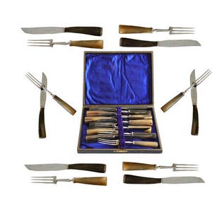 May include: A vintage cutlery set with knives and forks, featuring dark brown and tan handles and stainless steel blades. The set includes a box with a blue satin lining, showcasing the arranged silverware. The knives and forks are arranged in a decorative pattern.