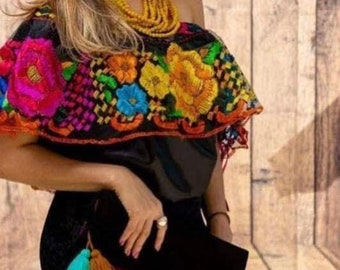 May include: A black off-the-shoulder top with colorful embroidered flowers. The top has a ruffled neckline and short sleeves.