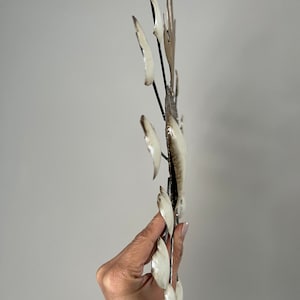 May include: White metal wall art with a sunburst design. The metal is shaped into leaves and has a distressed finish.