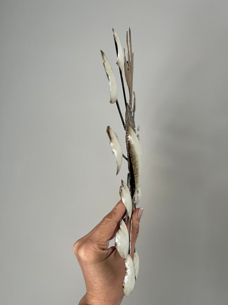 May include: White metal wall art with a sunburst design. The metal is shaped into leaves and has a distressed finish.