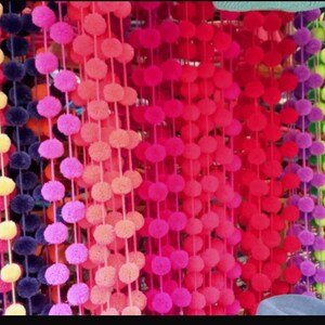 May include: A selection of colourful pom-pom trim, with strands of blue, yellow, pink, red, purple, green, and lime green pom-poms.