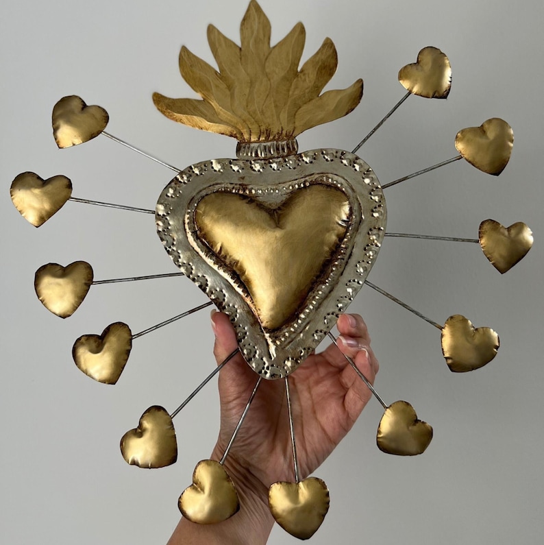 May include: A gold and silver metal heart with a flame design on top and 12 smaller hearts hanging from it.