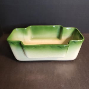 May include: A rectangular ceramic dish featuring a stepped rim design. The interior and exterior surfaces transition from a creamy off-white base colour at the bottom to a vibrant, deep green gradient along the upper edges and the rim.
