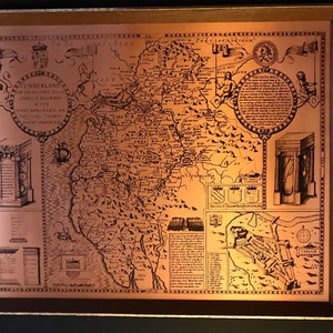 Puede incluir: Un mapa enmarcado de color cobre de Cumberland, Inglaterra, con ilustraciones detalladas de ciudades, monumentos y texto. El mapa incluye el texto "Cumberland and the Ancient Cities Carlisle Described". El marco es de color dorado.