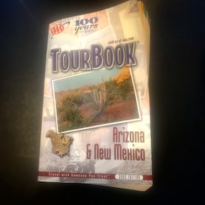 Puede incluir: Un libro de viajes AAA para Arizona y Nuevo México. La portada presenta una foto de un paisaje desértico con un cactus y el texto "Travel with Someone You Trust" y "2002 Edition".