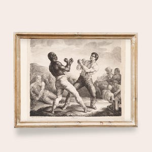 May include: Framed black and white print depicting a boxing match between two men. The artwork shows the boxers in action, surrounded by a crowd of onlookers. The frame is a light brown color.