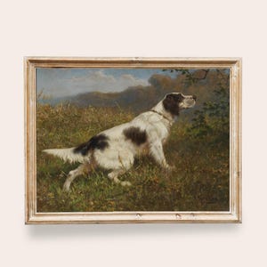 Puede incluir: Pintura antigua enmarcada de un perro en un campo. El perro es blanco con manchas negras y marcas marrones. La obra de arte está enmarcada en un marco de madera dorada, con un fondo de paisaje de hierba verde, árboles y un cielo nublado.