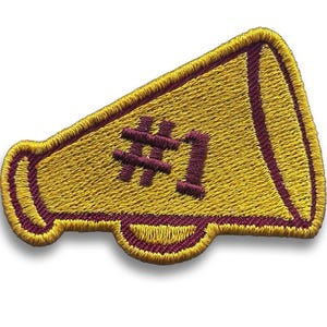May include: Embroidered patch in the shape of a megaphone. The patch is yellow with maroon accents and the number "#1" embroidered in maroon. The patch has a stitched border and is likely for a cheerleader or sports team.