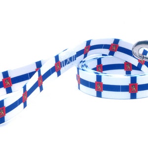 May include: A blue and white dog leash with a repeating pattern of the Finnish flag. The leash has a silver metal clip.
