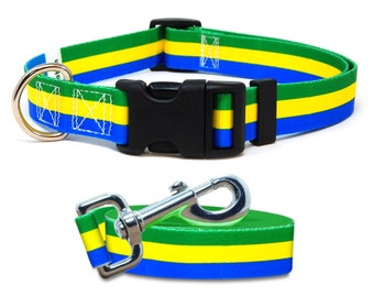 May include: A dog collar and leash set with a green, yellow, and blue striped pattern. The collar has a black plastic buckle and a silver metal D-ring. The leash has a matching striped pattern and a silver metal clasp.