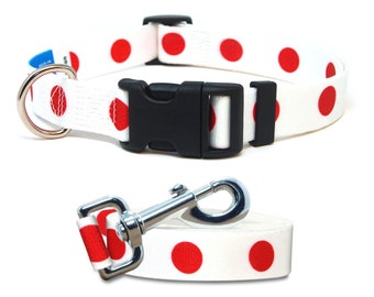 May include: White dog collar and leash with red polka dots. The collar has a black plastic buckle and a silver D-ring. The leash has a silver clip.