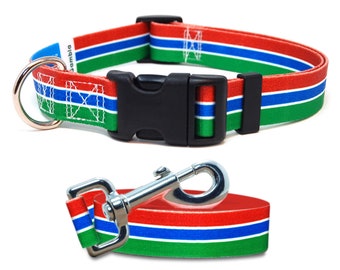 May include: A red, blue, and green dog collar with a black buckle and a matching leash with a silver clip. The collar and leash feature the colors of the Gambian flag.