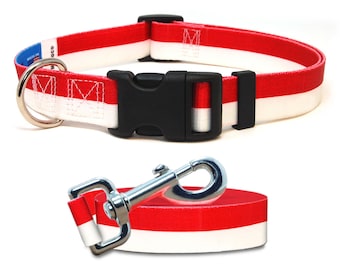 May include: Red and white dog collar with a black buckle and a silver D-ring. The collar is made of a durable nylon material and features a red and white striped pattern. The collar is also equipped with a silver clip for attaching a leash.