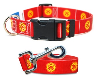 May include: Red dog collar and leash with a repeating pattern of the flag of Kyrgyzstan. The flag features a yellow sun with 40 rays on a red background.