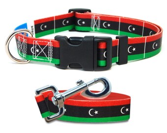 May include: A dog collar and leash set featuring the flag of Libya. The collar and leash have a black, red, and green striped pattern with white crescent moons and stars. The collar has a black plastic buckle and a metal D-ring.