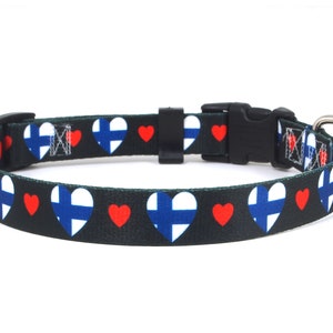 May include: A black dog collar with a repeating pattern of red hearts and white and blue Finnish flags in heart shapes.