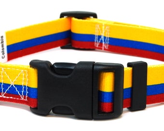 May include: A yellow, blue, and red dog collar with a black buckle and a silver D-ring. The collar has the word "Colombia" printed on it.