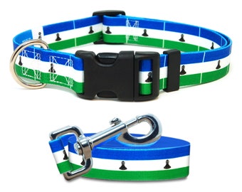 May include: A blue, white, and green dog collar and leash with the flag of Lesotho printed on them. The collar has a black plastic buckle and a silver D-ring. The leash has a silver clip.