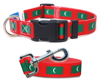 May include: Red dog collar and leash set featuring the flag of the Maldives. The collar has a black plastic buckle and a metal D-ring. The leash has a metal clasp. The flag design includes green rectangles with a white crescent moon.
