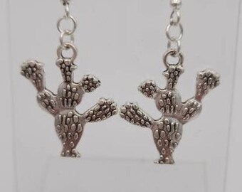 May include: A pair of silver dangle earrings featuring a cactus design. The earrings have a simple hook closure.
