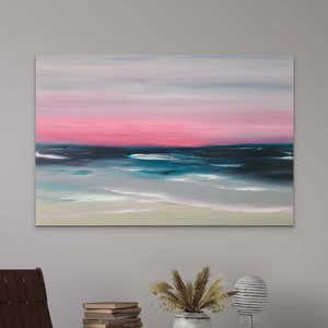 May include: Abstract painting of a seascape with a pink and blue sky over a dark blue ocean with white waves. The painting is on a canvas and is framed.