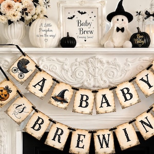May include: A two-tiered Halloween-themed banner featuring diamond and square-shaped paper cards strung together with black ribbon. The cards display the text A BABY IS BREWING in black gothic font, interspersed with illustrations of pumpkins, a witch hat, and a baby carriage.