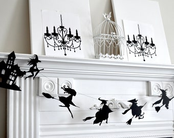 May include: Black and white Halloween paper garland with a haunted house, witches flying on broomsticks, and a chandelier. The garland is hanging above a white fireplace mantel.