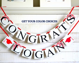 May include: Red and white graduation banner with the words "Congrats Logan" and red graduation caps on each end.