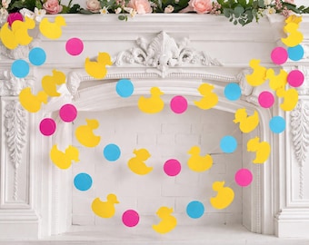 May include: A white fireplace mantel decorated with a garland of yellow duck cutouts, pink circles, and blue circles. The mantel is adorned with floral arrangements of pink and white flowers.