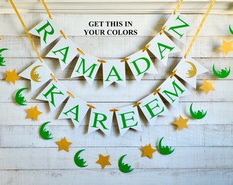 May include: White and green Ramadan Kareem banner with gold stars and crescent moons. The banner is strung on a white wooden background. The text "Get this in your colors" is printed above the banner.