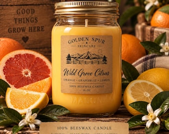 May include: A 16 oz yellow beeswax candle in a clear glass mason jar with a gold lid. The label reads Golden Spur Skincare Wild Grove Citrus Orange Grapefruit Lemon. The candle is surrounded by fresh grapefruit, orange, and lemon slices.