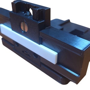 May include: A black 3D printed camera mount with a white plastic slider. The mount has a screw hole and a slot for a camera.