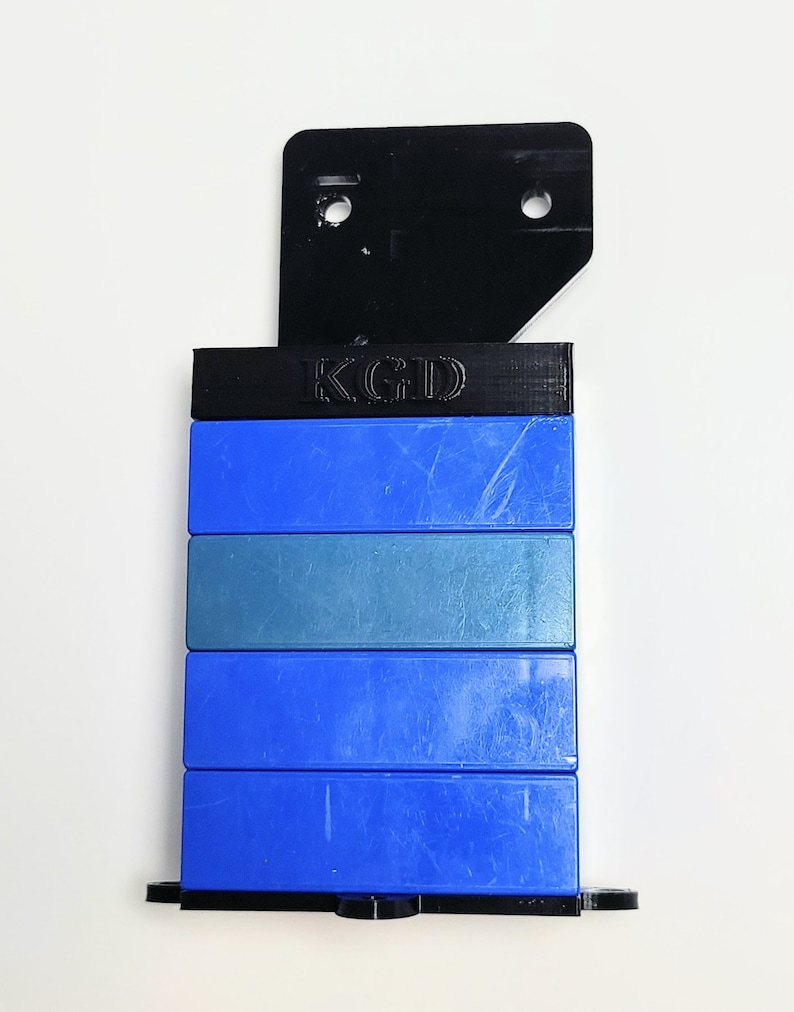 May include: A stack of blue and gray plastic blocks with a black plastic top piece. The top piece has the letters "KGD" printed on it.