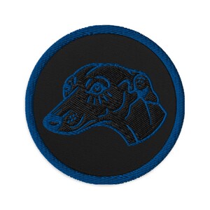 May include: Embroidered patch featuring a black dog head profile with blue stitching on a black circular background. The patch has a blue border and is likely for clothing or accessories.