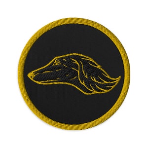 May include: Embroidered patch featuring a black dog head profile on a black circular background. The dog's silhouette is detailed with yellow thread, and the patch has a yellow border. The design is suitable for jackets, bags, or other fabric items.
