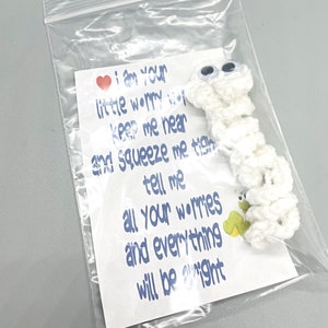 May include: A white crocheted worry worm with googly eyes, packaged in a clear plastic bag. A card inside reads "I am your little worry worm...and everything will be alright."