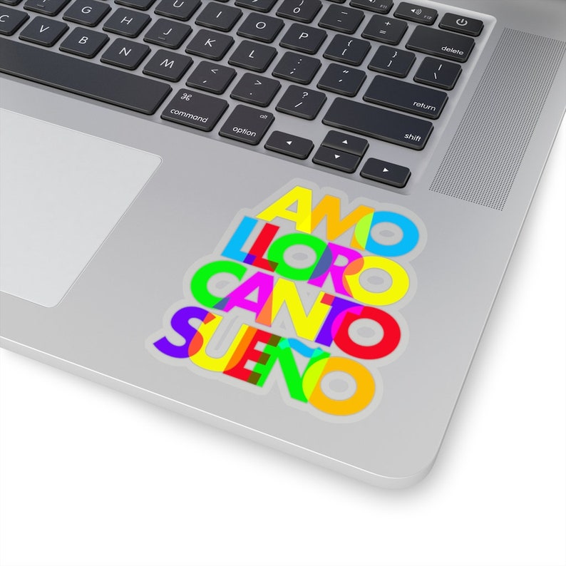 May include: A sticker with the Spanish words "AMO", "LLORO", "CANTO", and "SUE&Ntilde;O" stacked on top of each other. The words are in different colors, including red, yellow, green, blue, and pink.