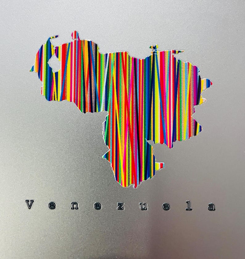May include: A silver-colored artwork featuring the outline of Venezuela filled with vertical stripes in various colors. The word "Venezuela" is printed in black letters below the map.