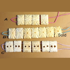 May include: Three rows of carved bone beads, each row strung on a different colored cord. The top row is labeled "A", the middle row is labeled "B" and the bottom row is labeled "C". The middle row is labeled "Sold".