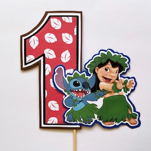 Könnte beinhalten: Ein farbenfroher Tortenaufsatz mit der Zahl "1" mit rotem Hintergrund und weißem Blättermuster. Der Aufsatz enthält auch die Zeichentrickfiguren Lilo und Stitch, mit einem Holzstab zum Einsetzen in einen Kuchen. Die Figuren sind blau umrandet.