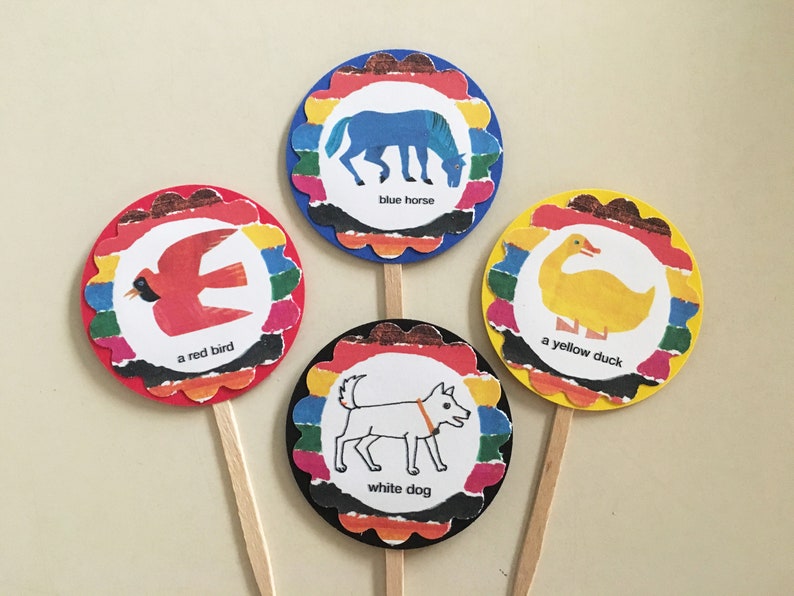 May include: Four colorful cupcake toppers with images of a blue horse, a red bird, a yellow duck, and a white dog. Each topper has a scalloped edge and a rainbow stripe design. The text on each topper reads "blue horse", "a red bird", "a yellow duck", and "white dog".