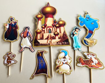 May include: A collection of Aladdin-themed cupcake toppers. The toppers feature characters like Aladdin, Jasmine, Genie, Jafar, Abu, and Rajah, along with the palace and a magic carpet. Each character is outlined in gold glitter and attached to a wooden stick.