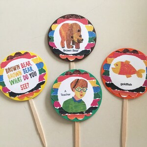 May include: Four colorful round cupcake toppers with scalloped edges. Each topper features an illustration from the children's book "Brown Bear, Brown Bear, What Do You See?" The toppers include a brown bear, a goldfish, a teacher, and the text "Brown Bear, Brown Bear. What Do You See?"